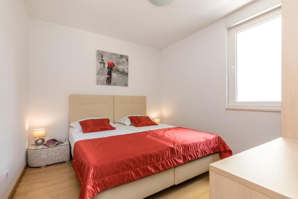a bedroom with a bed with a red blanket at Apartment Marcela With Private Parking in Split