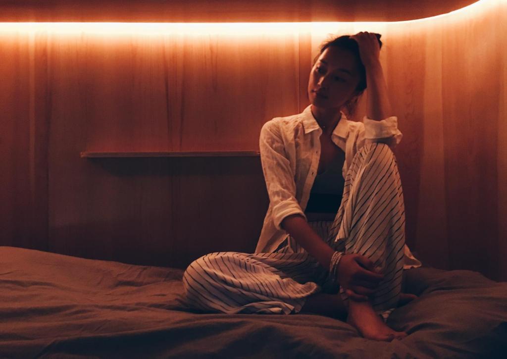 a woman sitting on a bed in a room at SLEEEP HKG Gough St in Hong Kong