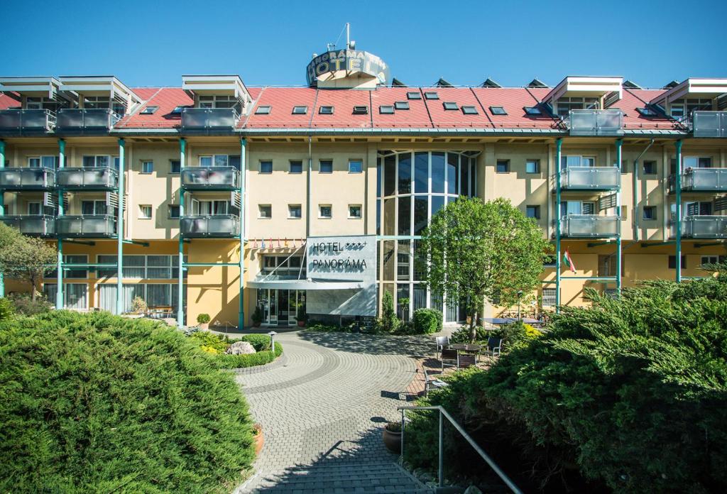 ein großes Gebäude mit einem Gehweg davor in der Unterkunft Hotel Panoráma in Balatongyörök