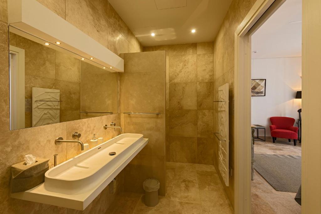 a bathroom with a sink and a red chair at The Snop House in Senglea