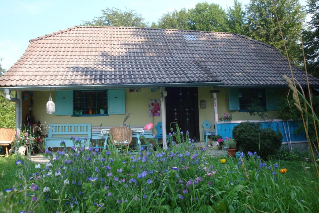 una casa con un jardín con flores púrpuras en Blue Cottage en Podvrh