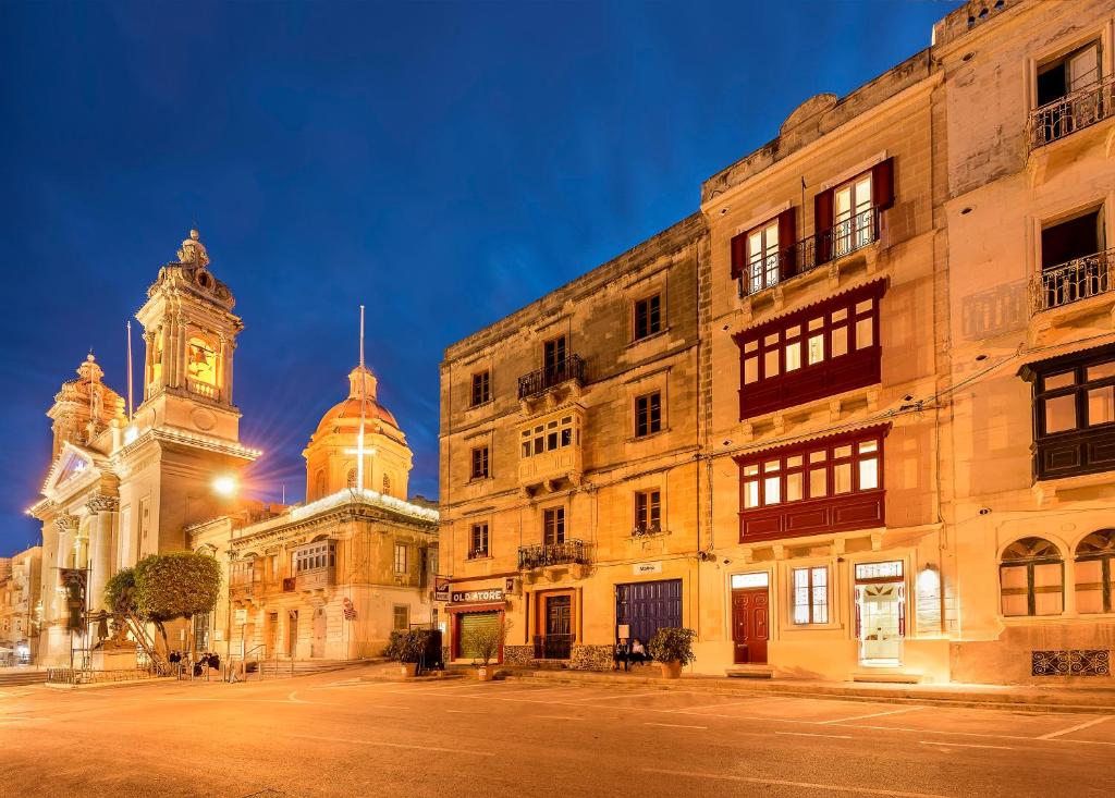 a building with a clock tower next to a street at The Snop House in Senglea