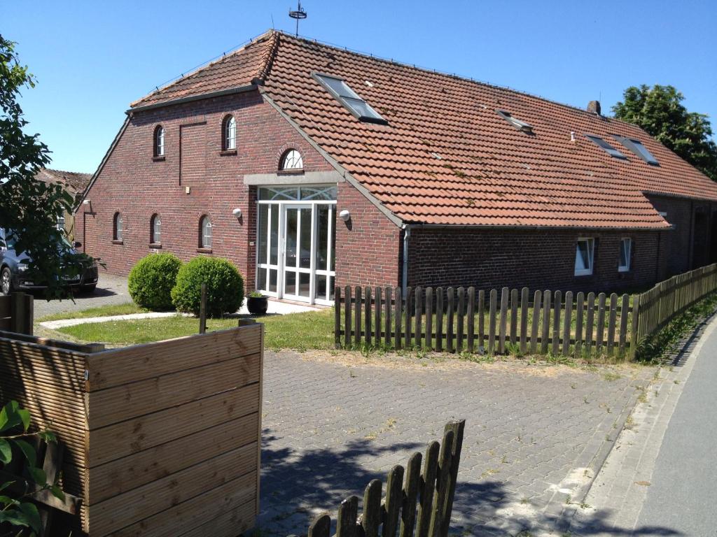 a brick building with a wooden fence in front of it at Ferienwohnungen Am Mühlenhügel in Stedesdorf