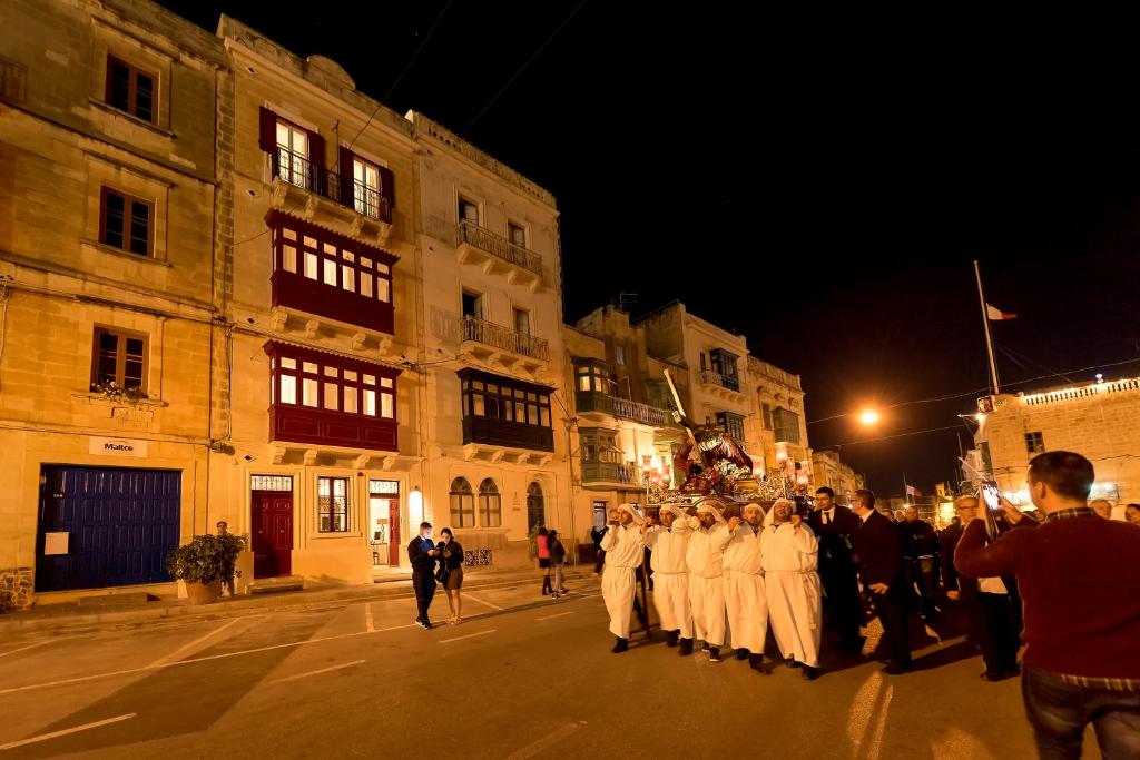 a group of people standing in a street at night at The Snop House in Senglea
