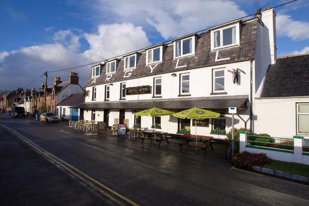 a building with tables and umbrellas on a street at Argyll Hotel in Ullapool