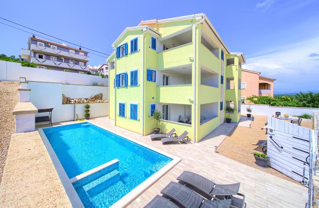 - un bâtiment avec une piscine à côté d'un bâtiment dans l'établissement Apartments Mali Nono, à Krk