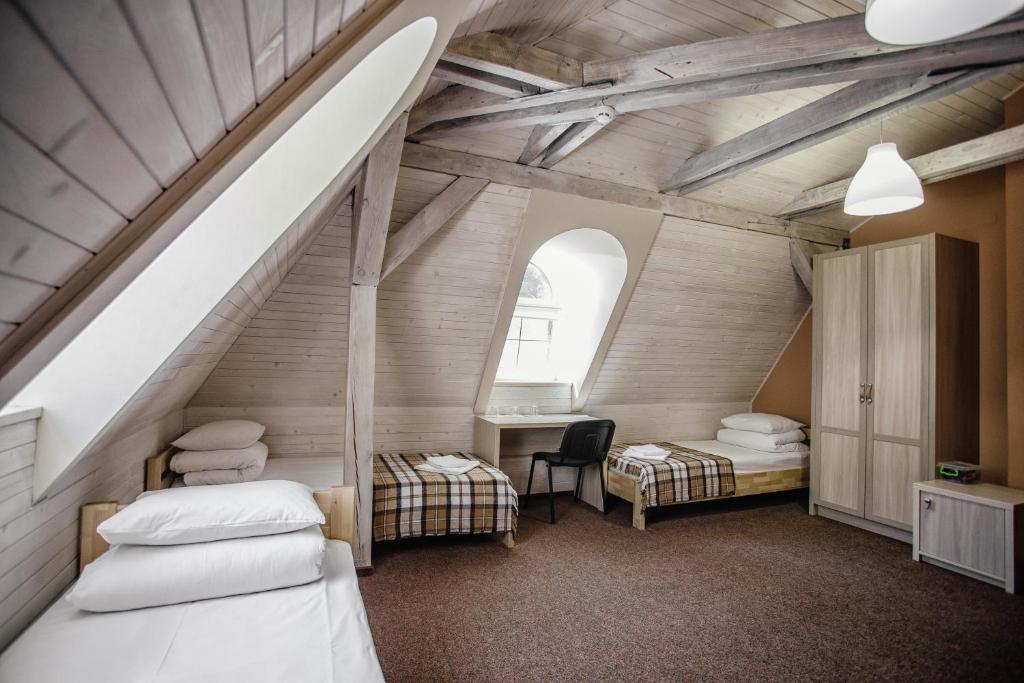 a attic room with two beds and a staircase at Guest House "Arkhistratyg" in Lviv