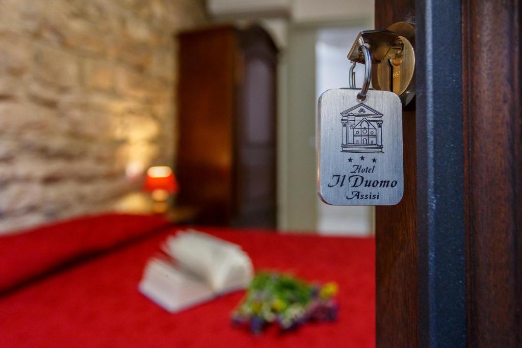 Hotel Il Duomo في أسيسي: معلقة على باب مع طاولة حمراء