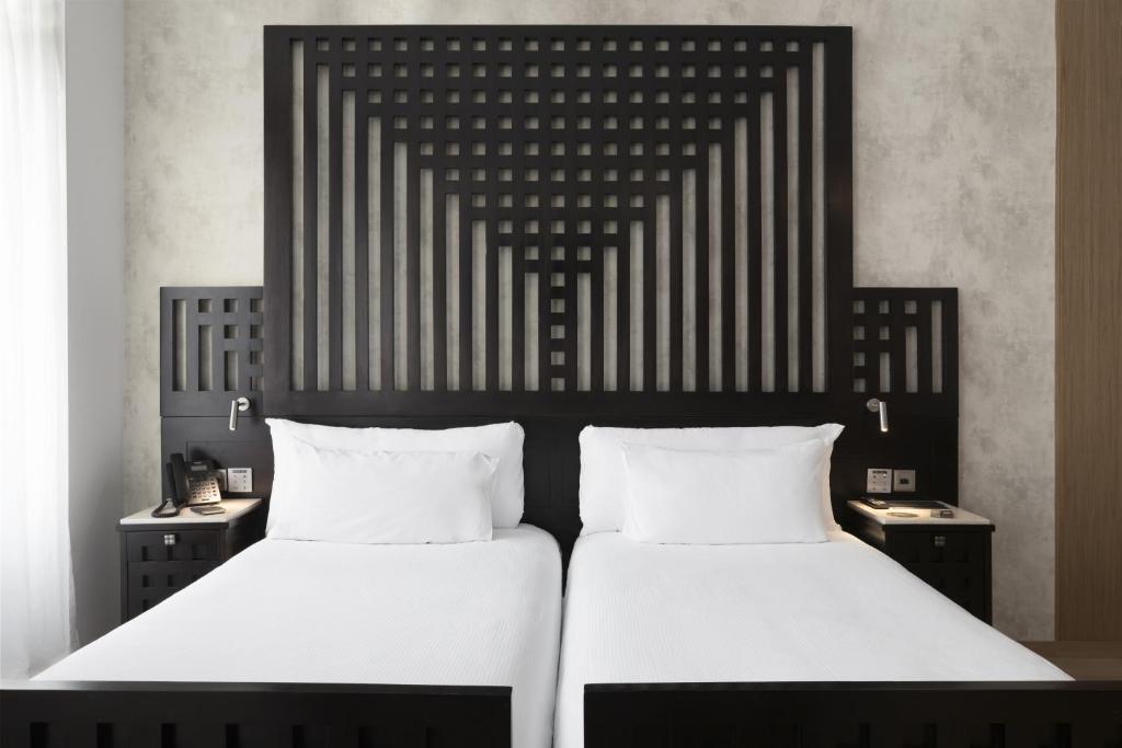 um quarto com 2 camas e lençóis brancos em ICON Casona 1900 em Madri