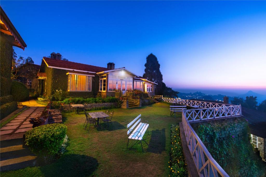 a house with a yard with chairs and a fence at Villa Retreat - Boutique Hotel in Kodaikānāl