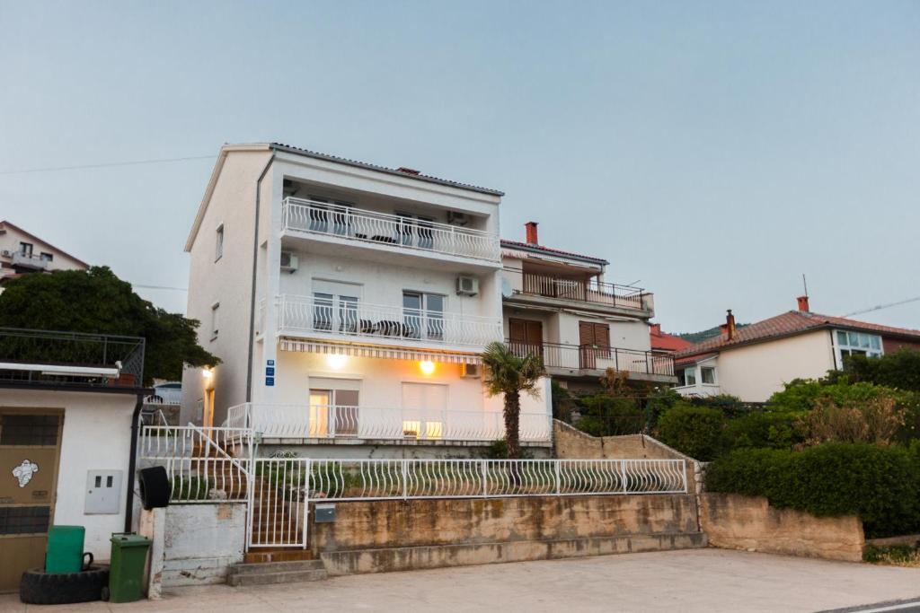 une maison blanche avec une clôture devant elle dans l'établissement Apartmani Kristijan, à Crikvenica