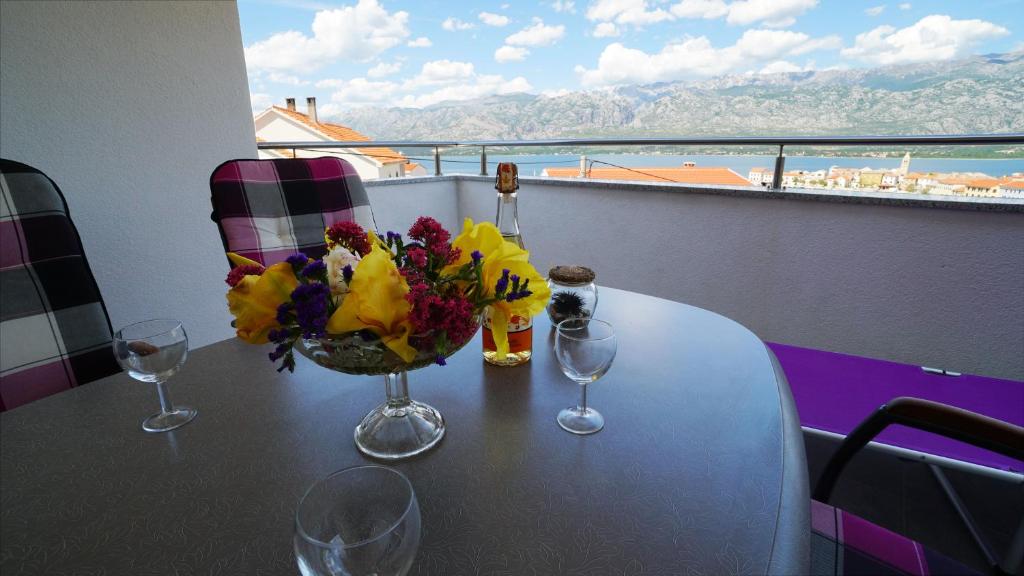 a table with a vase of flowers and wine glasses at Apartment Ana in Vinjerac