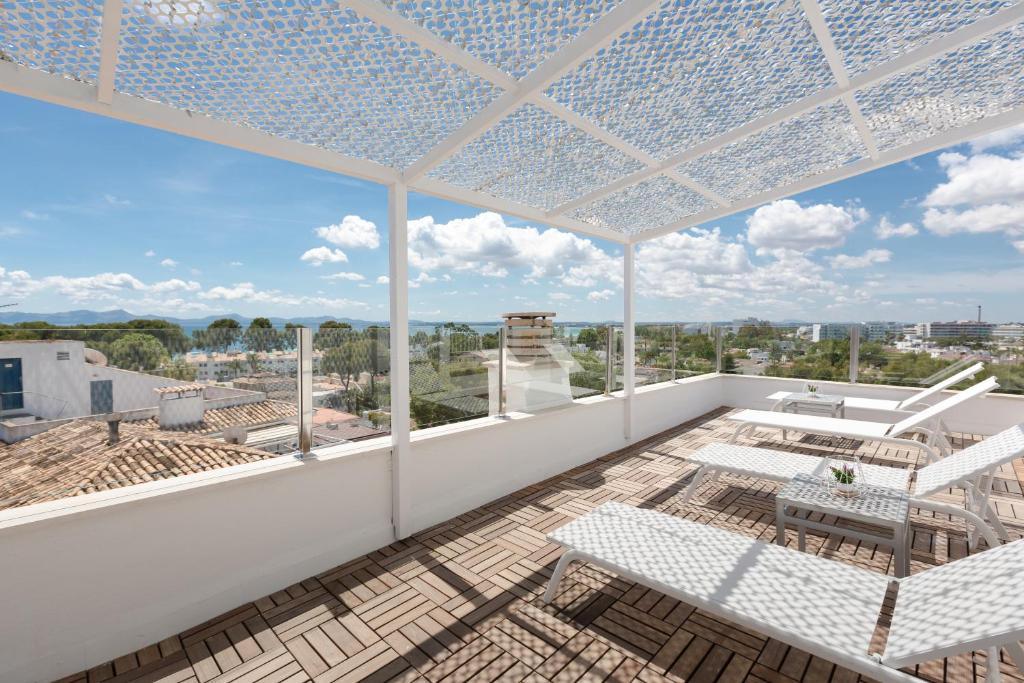 a patio area with chairs, tables and umbrellas at Apartamentos Ferrer Tamarindos in Port d'Alcudia