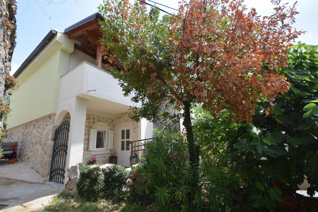 a house with a tree in front of it at Apartments Neven in Čižići