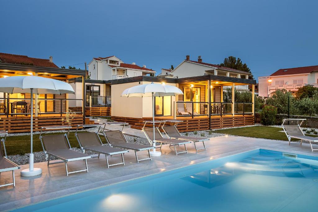 a house with a swimming pool with chairs and umbrellas at Mobile Homes Sanmar in Punat