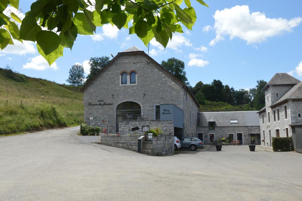 a stone barn with a car parked in a parking lot at Les gîtes "Cœur de ferme" in Celles