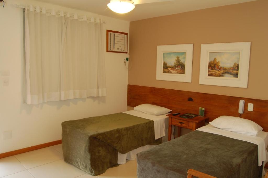 a hotel room with two beds and a window at Palmier Hotel & Convenções in Itaboraí