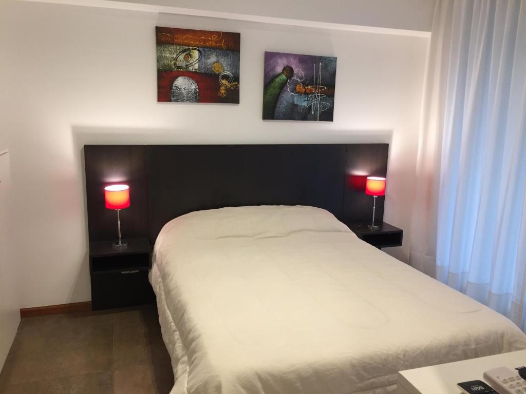 1 dormitorio con 1 cama blanca y 2 lámparas en Departamento moderno en Rosario