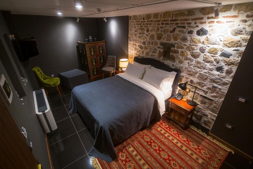 um quarto com uma cama e uma parede de pedra em HANI I PAZARIT Boutique Hotel em Korçë
