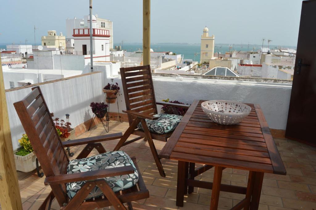 drewniany stół i krzesła na balkonie z latarnią morską w obiekcie Apartamento El Mirador de Cadiz w Kadyksie