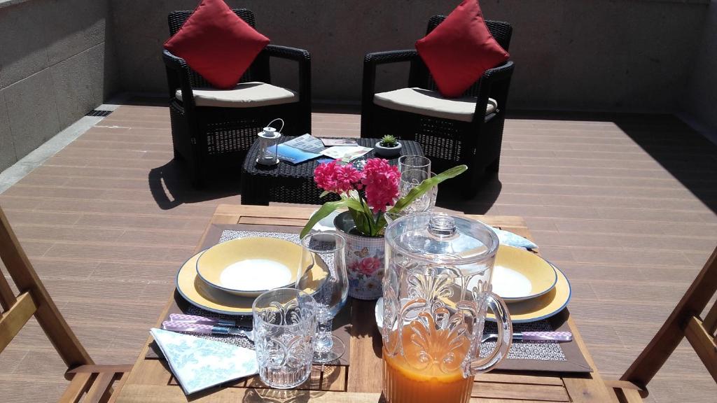 einen Tisch mit Platten und eine Vase Blumen darauf in der Unterkunft Apartamento Avenida in Ponte de Lima