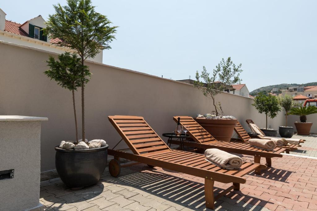 a row of lounge chairs on a patio with trees at Apartments Siblings in Mokošica