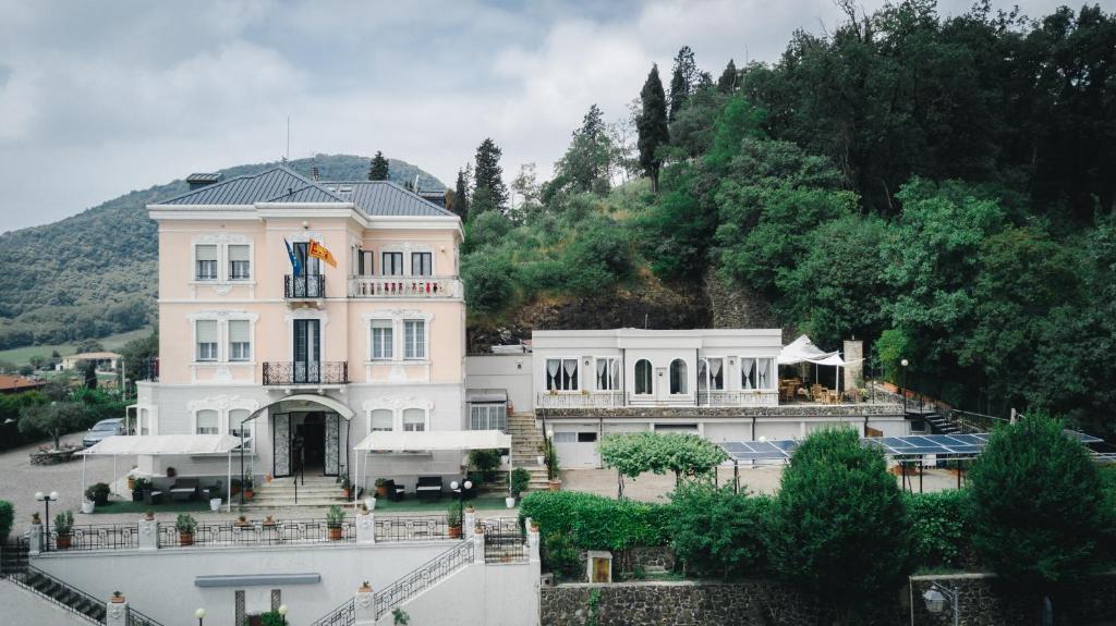 uma grande casa branca numa colina com árvores em Villa Lussana em Teolo