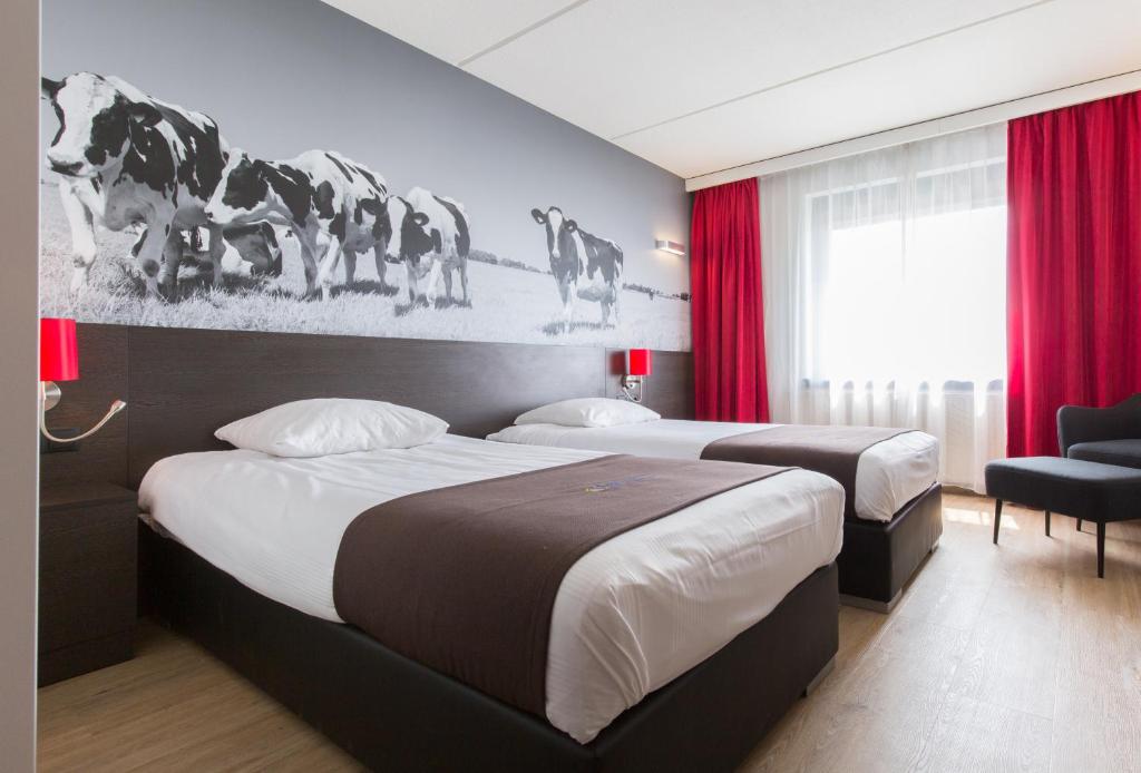 two beds in a hotel room with red curtains at Bastion Hotel Almere in Almere