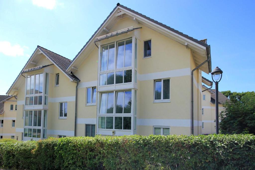 a large yellow building with windows and a hedge at Wohnpark Stadt Hamburg by Rujana in Binz