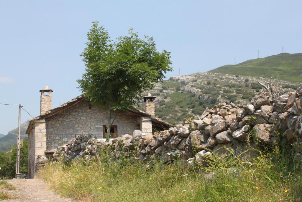 an old stone house with a tree on top at Casa Rural Las Machorras I y II in Bárcenas
