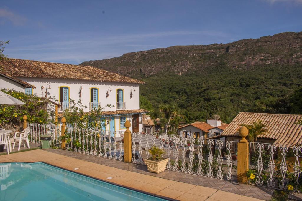 a house with a fence and a swimming pool at Pousada Hospedaria da Villa in Tiradentes