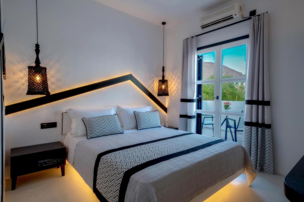 a white bedroom with a bed and a window at Divelia Hotel in Perissa