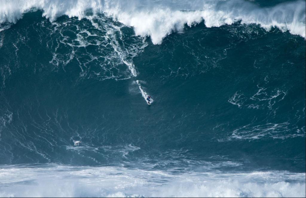 a surfer riding a large wave in the ocean at Beach House Ericeira in Ericeira