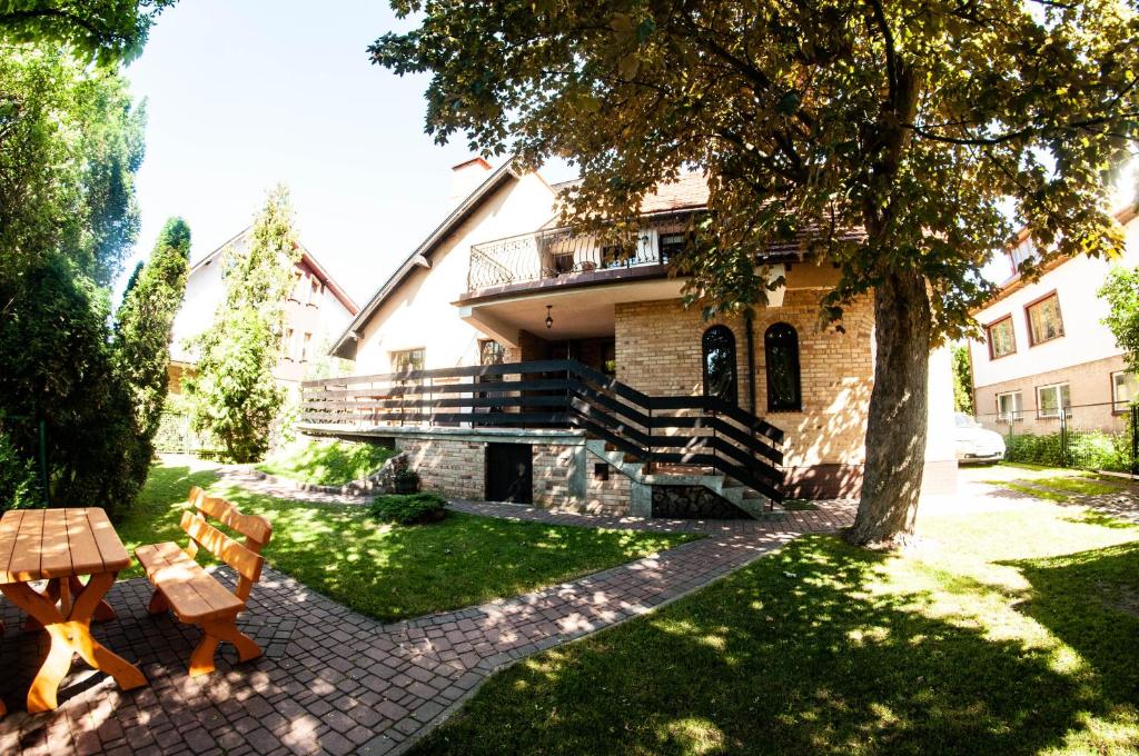 a house with a tree and a table and chairs at Willa Goscinny Dom in Kołobrzeg