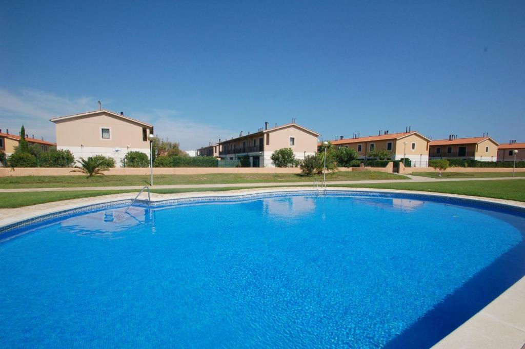 a large blue swimming pool with houses in the background at Daró 3D 37 Airco Mas Pinell in Torroella de Montgrí
