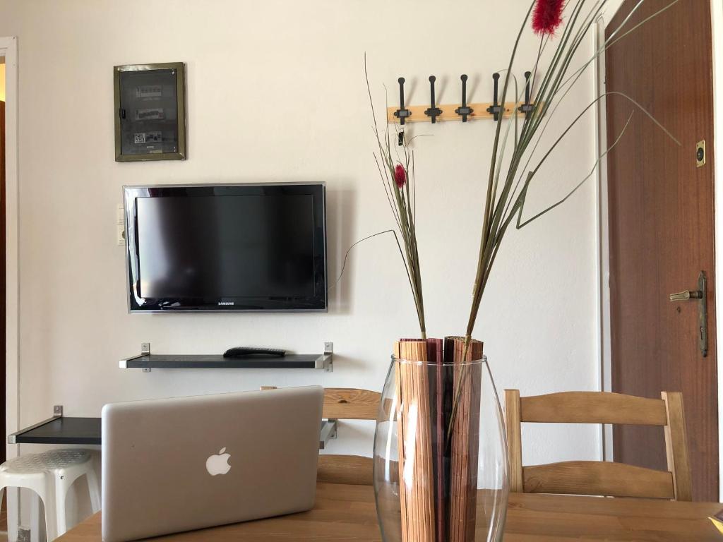 a vase with flowers in it sitting on a table with a laptop at Summer House close to the sea @ Almiri, Corinth in Kórinthos