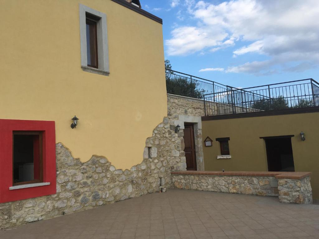 B&B Pegaso في San Pietro Infine: مبنى اصفر مع باب احمر وجدار حجري