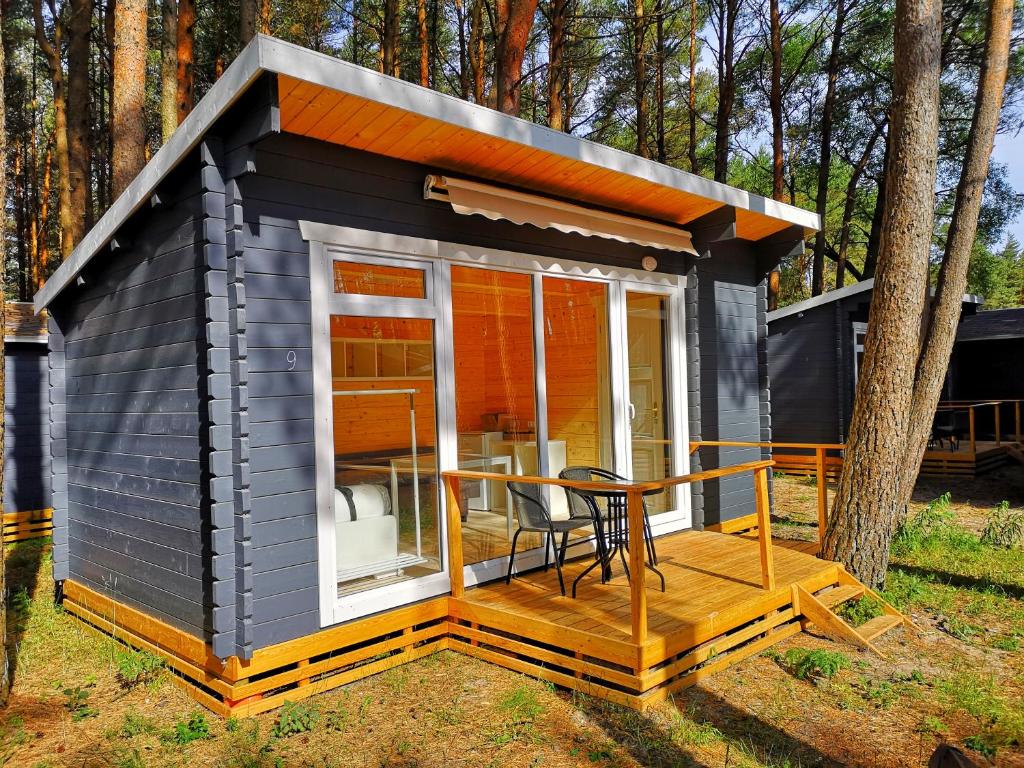a black tiny house with a table on a deck at Ku kū in Šventoji