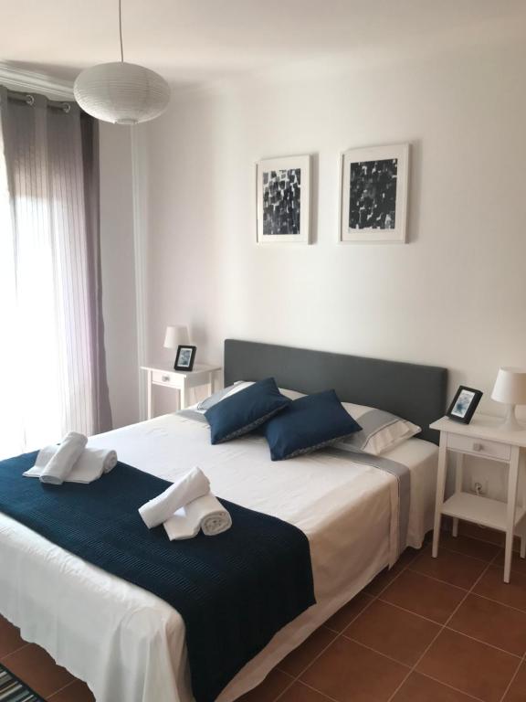 a bedroom with a large bed with blue pillows at Apartamento POR DO SOL in Aljezur