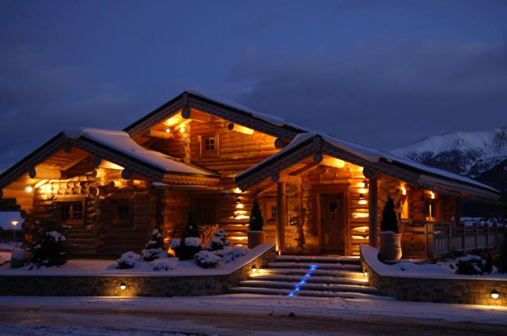 une cabane en rondins avec des lumières dans la neige la nuit dans l'établissement Chalet de luxe "Lodge des Sens" - Jacuzzi & Sauna - 12 pers, à Bolquère-Pyrénées 2000