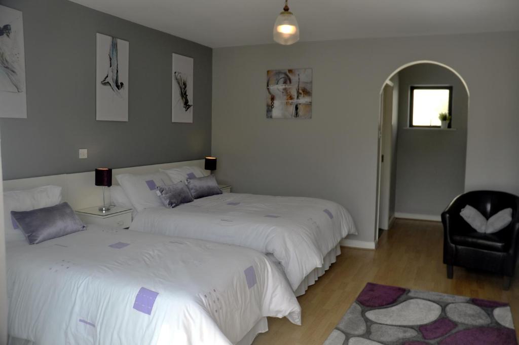1 dormitorio con 2 camas, silla y ventana en Shalom en Carlingford
