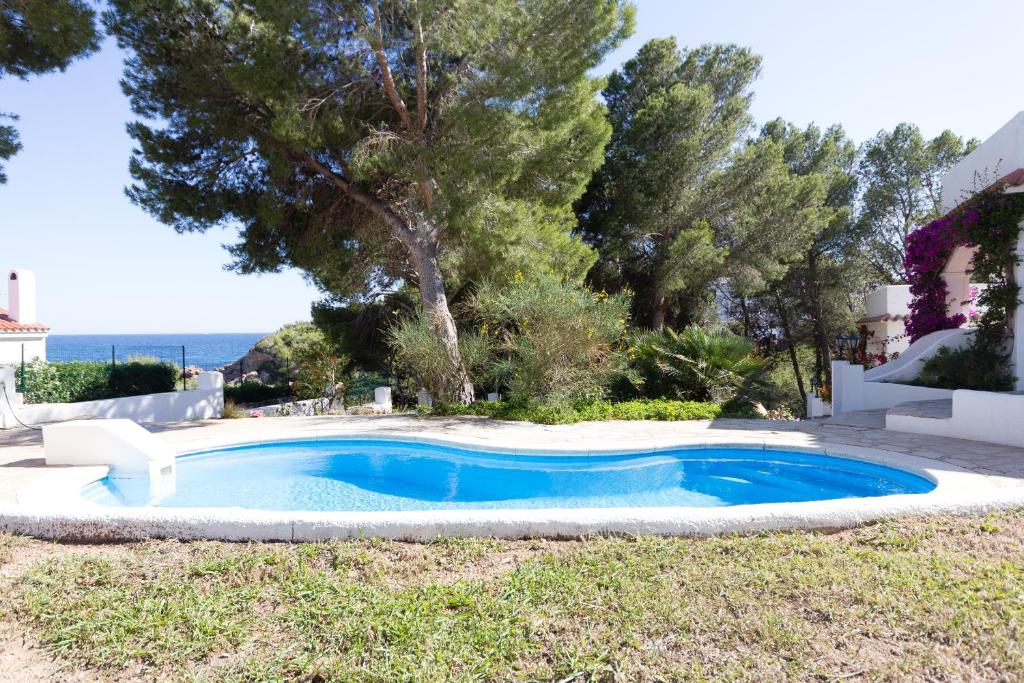 una piscina en un patio con árboles y el océano en INNOUTHOME Casa Piscina en L'Ametlla de Mar