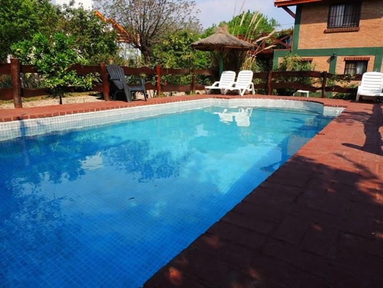 a large blue swimming pool with chairs and a house at Alma Mora in Merlo