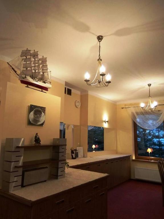 a living room with a chandelier and a kitchen at Dom Gościnny Emilia in Pobierowo