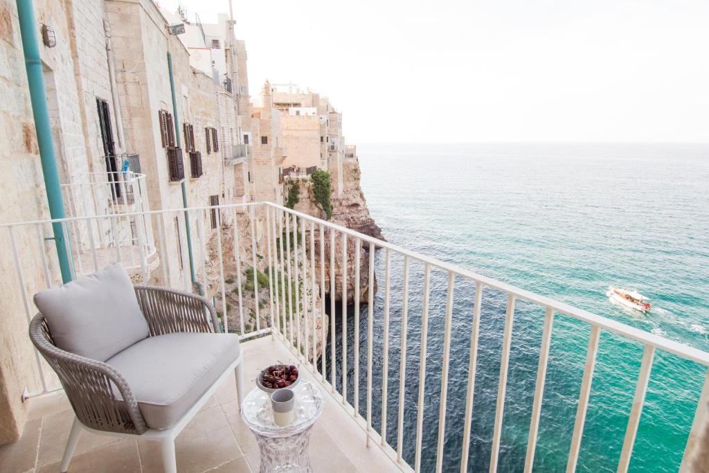 a chair sitting on a balcony overlooking the ocean at Dimora Talenti in Polignano a Mare