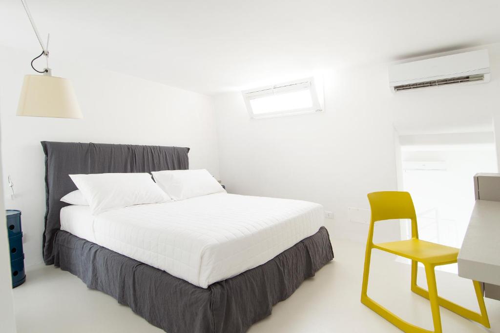 a white bedroom with a bed and a chair at Dimora Talenti in Polignano a Mare