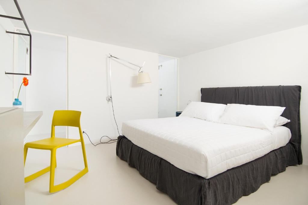 a white bedroom with a bed and a chair at Dimora Talenti in Polignano a Mare