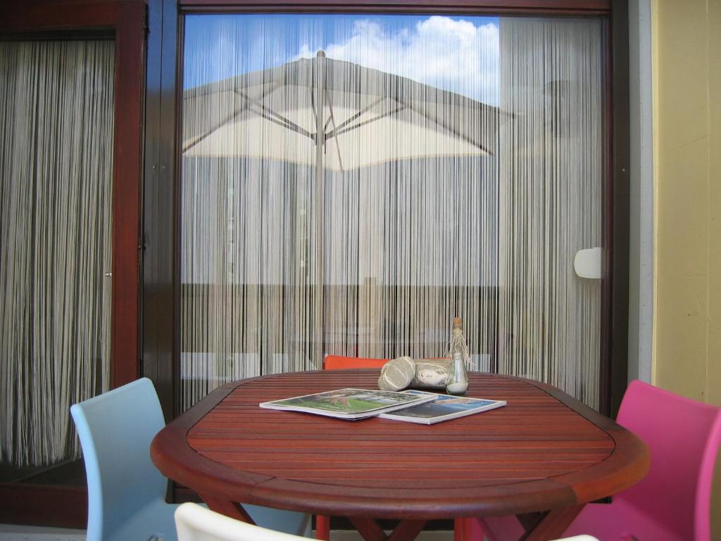 einen Esstisch mit einem Sonnenschirm vor dem Fenster in der Unterkunft Tróia Dreams in Troia