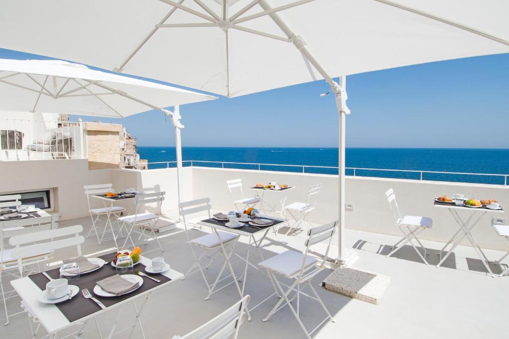 a balcony with white chairs and tables and the ocean at Dimora Talenti in Polignano a Mare