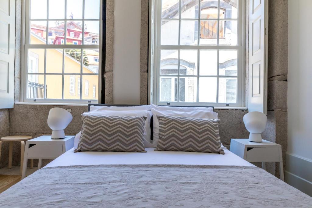 1 Schlafzimmer mit einem großen Bett und 2 Fenstern in der Unterkunft Vitoria Studio Residence II - Downtown in Porto